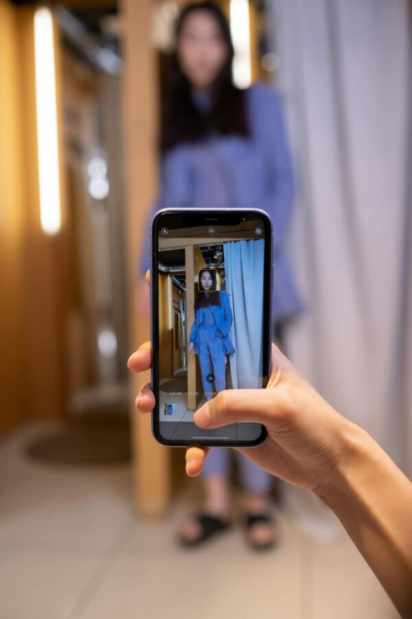 A woman captures an outfit photo with a smartphone in a stylish fitting room.