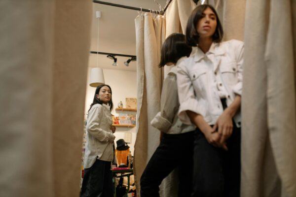 Women shopping and trying clothes in a fitting room with mirrors.